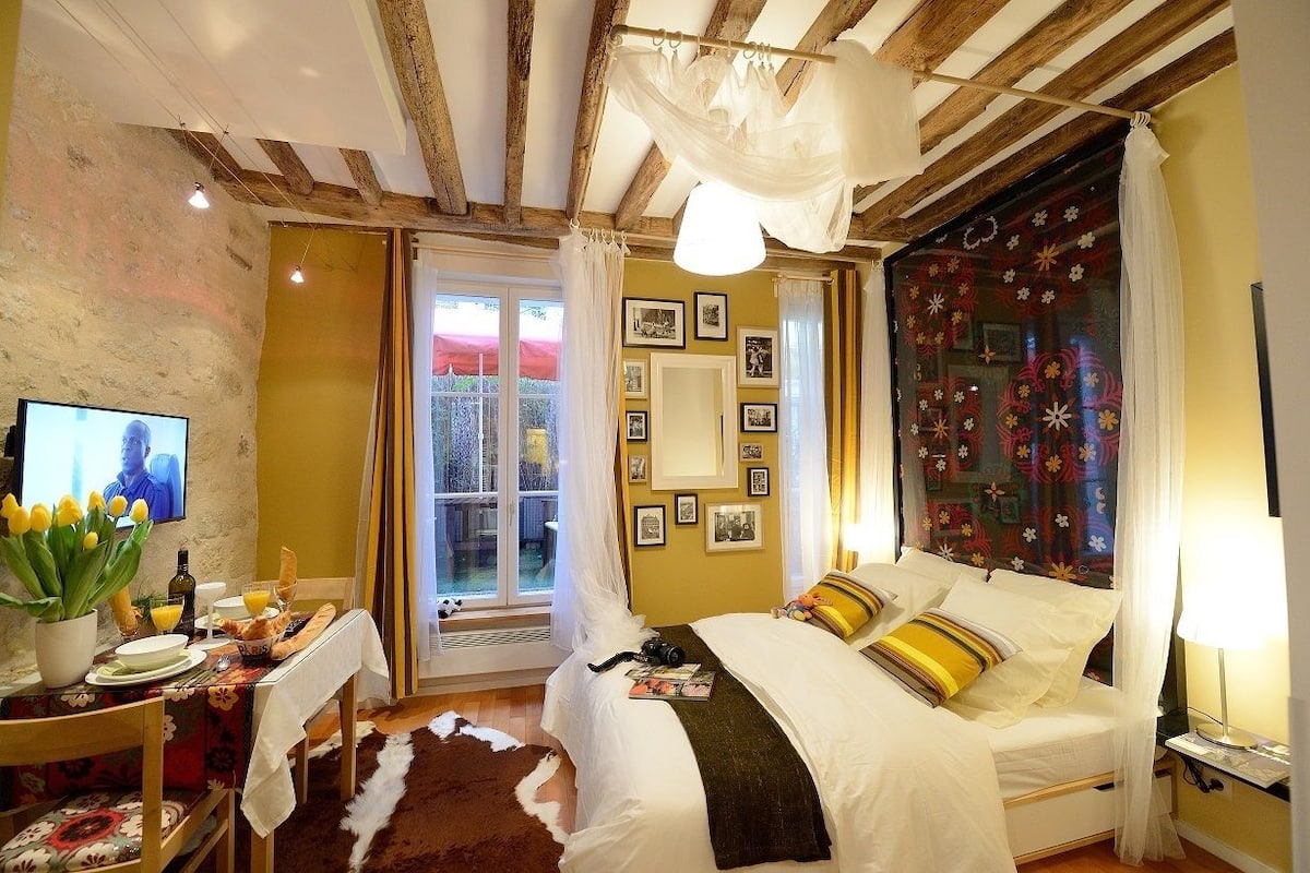 A bedroom with a bed, bedside table, and a window with curtains.