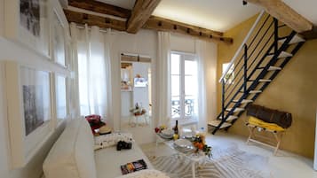 Ein geräumiges Wohnzimmer mit hohen Decken, einer Treppe und einem Balkon.