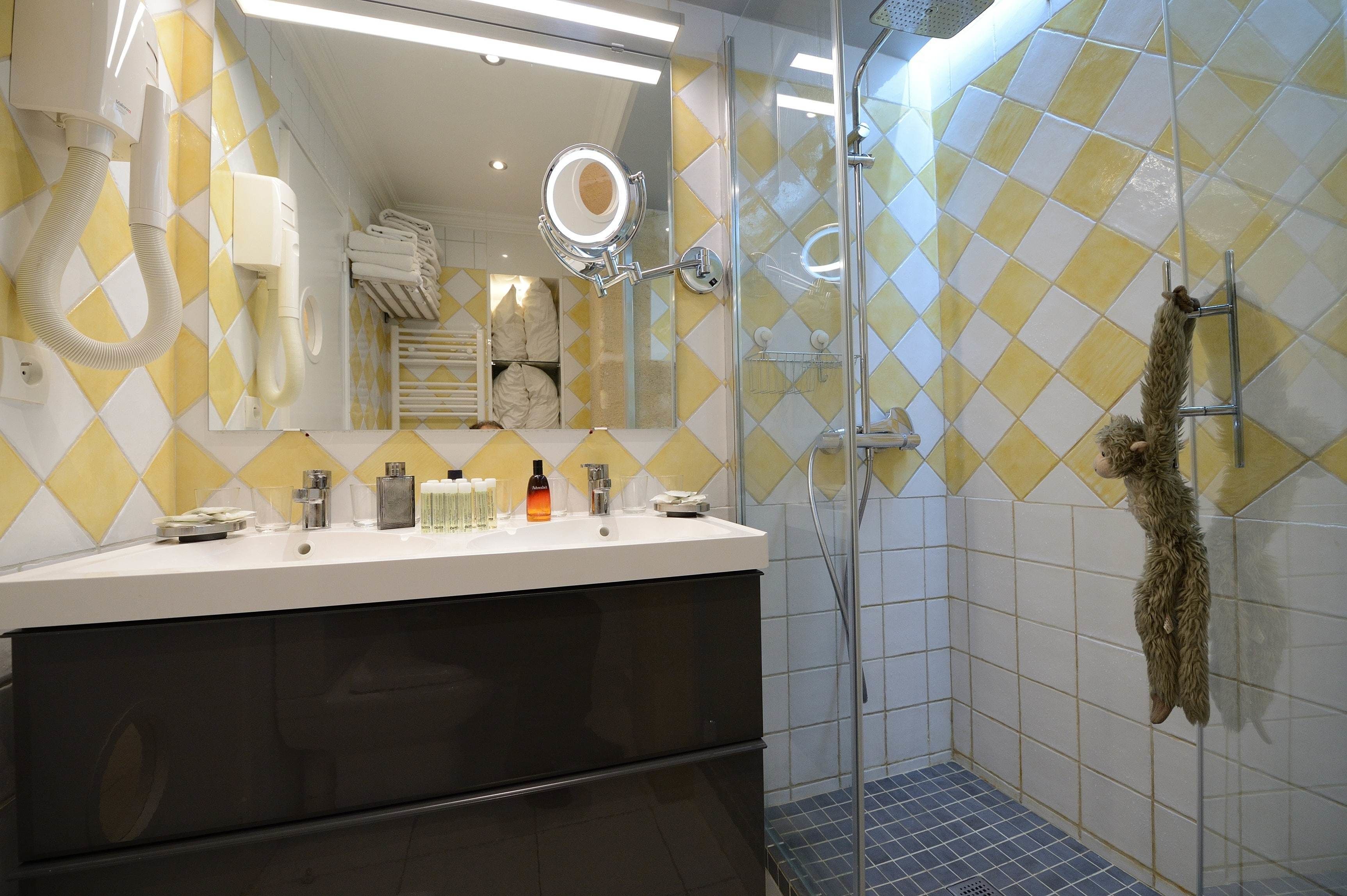 A bathroom with a mirror, sink, and shower.