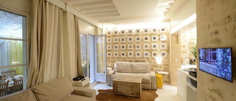 Un salon confortable avec un canapé, une table basse et un téléviseur fixé au mur.