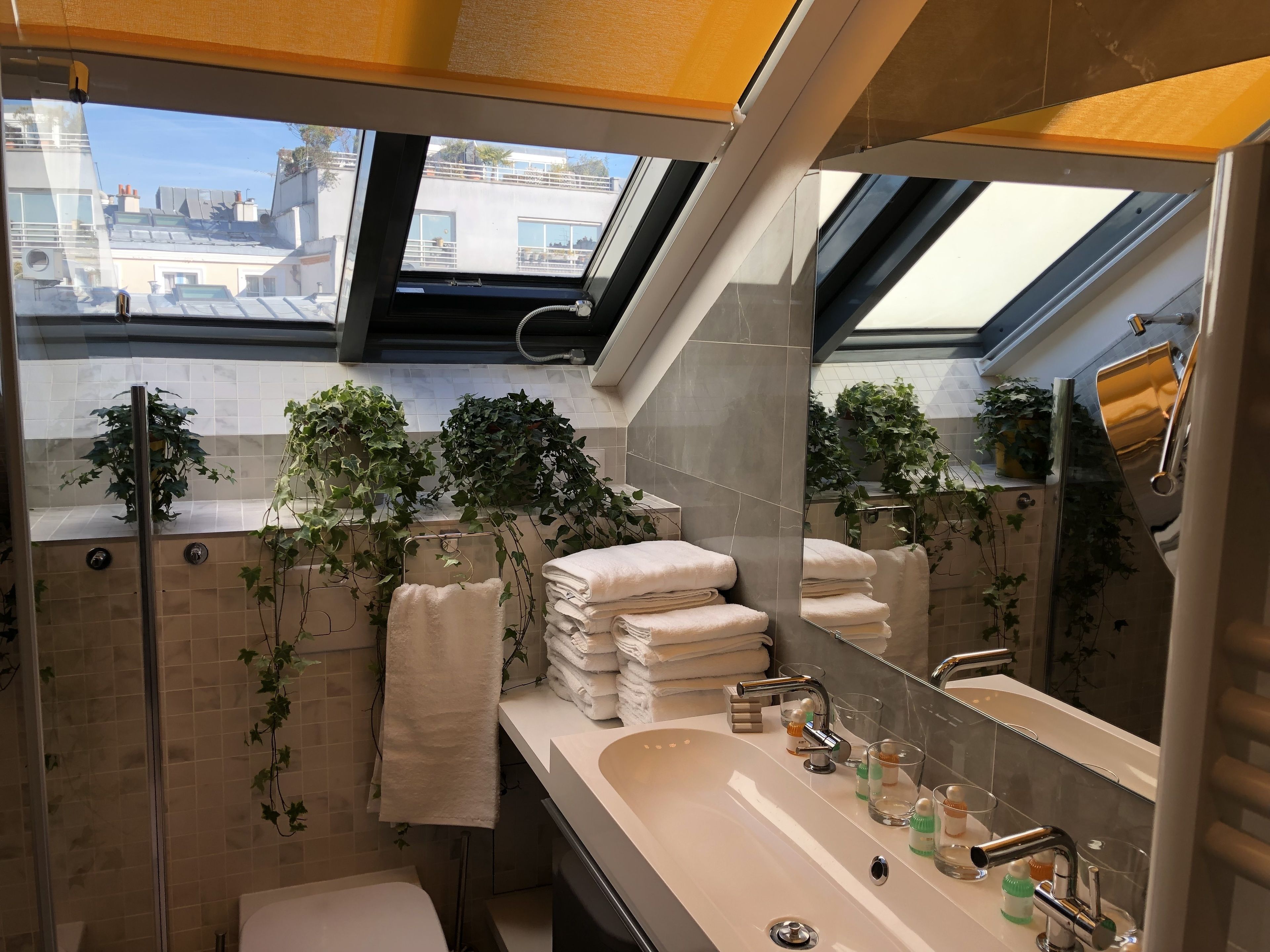 Un bagno moderno con una finestra a lucernario, uno specchio grande e un box doccia in vetro.