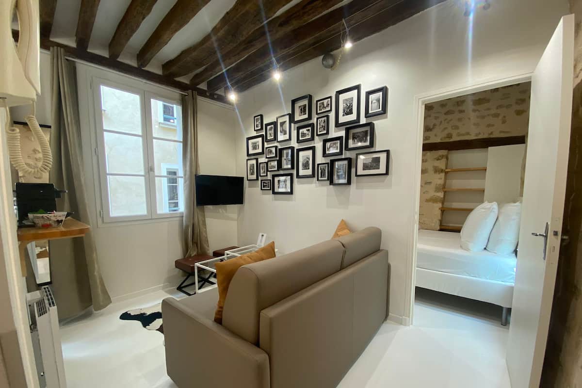 A modern room with a sofa, a bed, and a wall adorned with framed pictures.