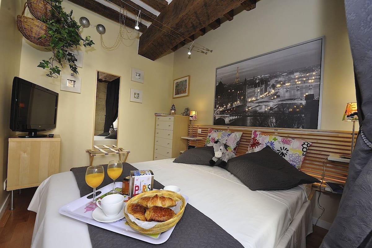 A hotel room with a bed, breakfast tray, television, and a cityscape view.