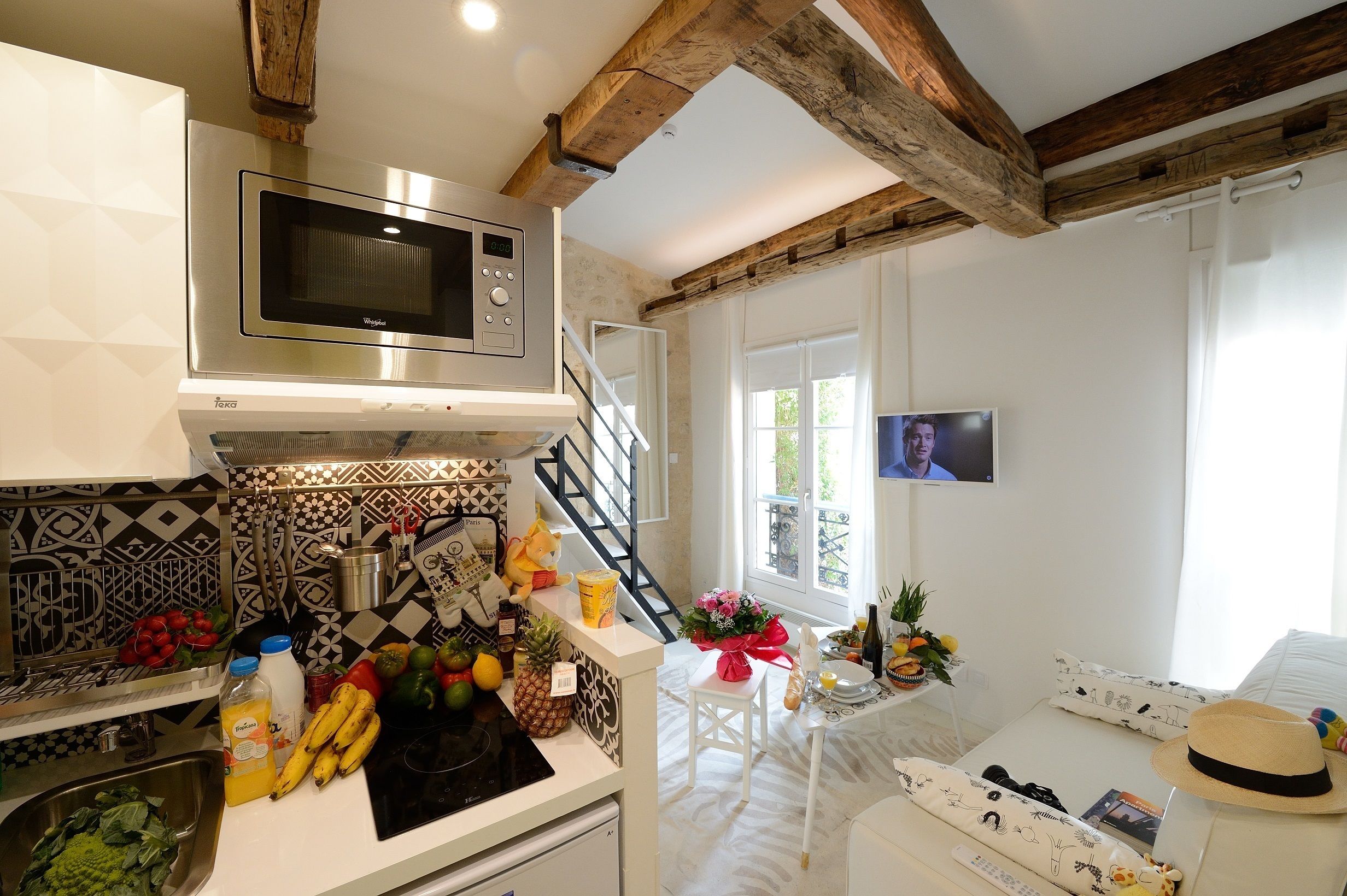 A modern kitchen with a microwave, a sink, and a dining area with a table set for two.
