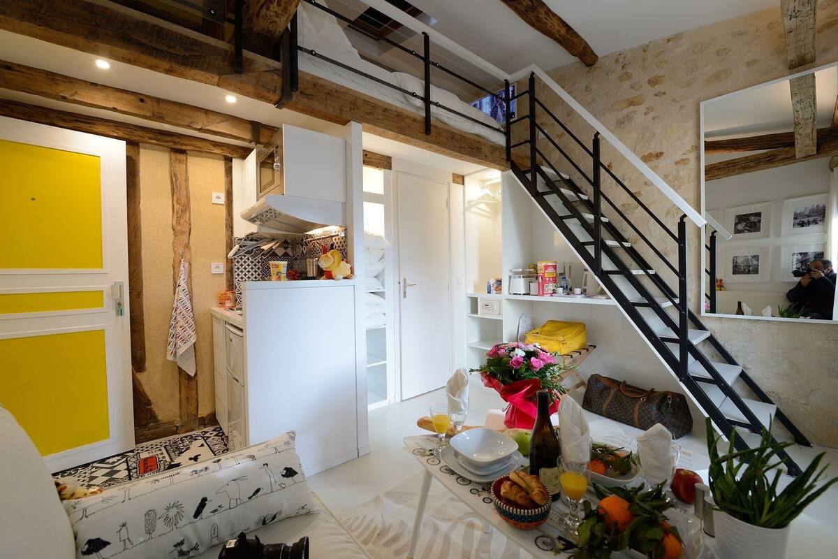A kitchen with a dining area, a staircase, and a yellow door.