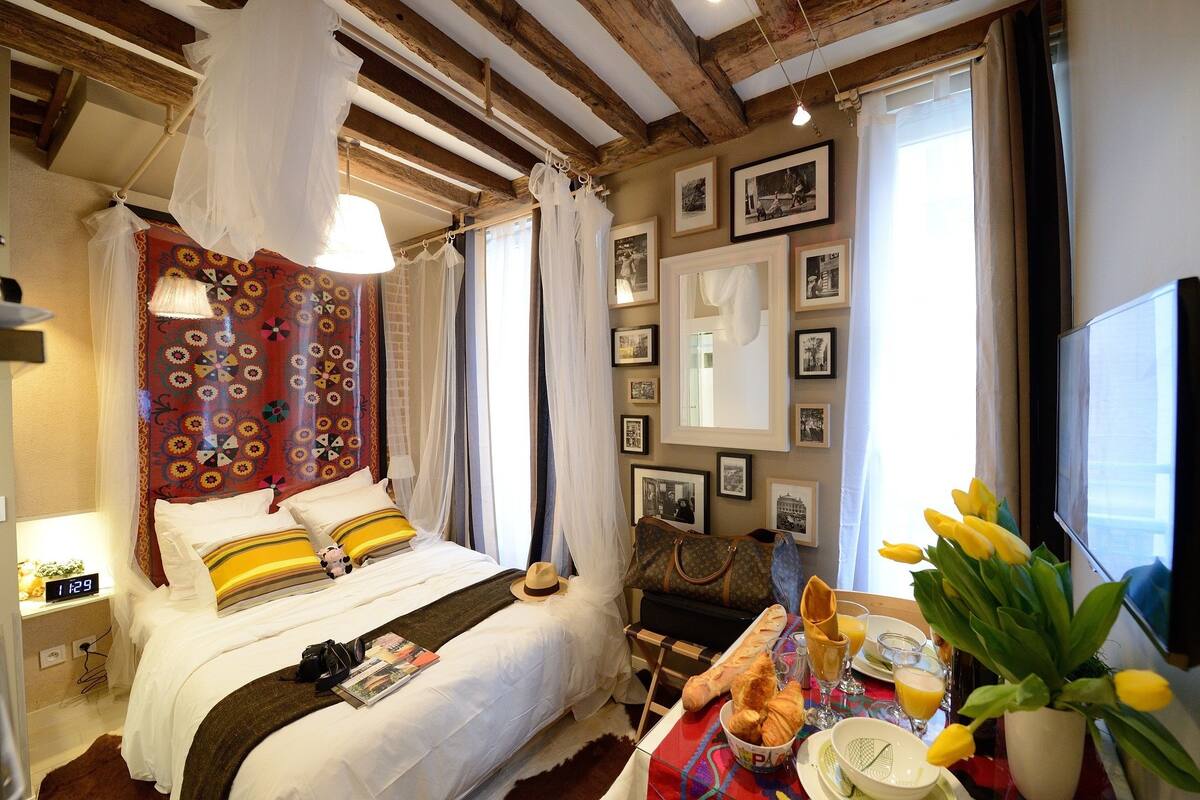 A cozy hotel room with a bed, a table with breakfast items, and a TV.
