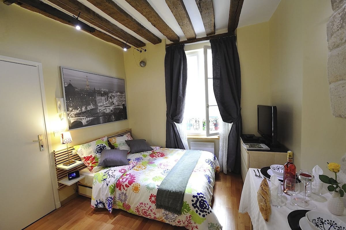 A bedroom with a bed, bedside table, lamp, and a window with curtains.