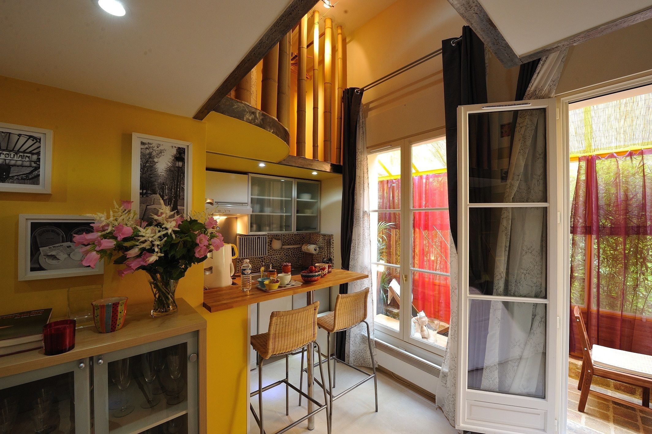 A kitchen with a wooden counter, bar stools, and a vase of flowers.