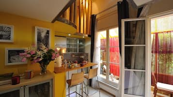 Una cocina con mostrador de madera, taburetes de bar y un florero con flores.