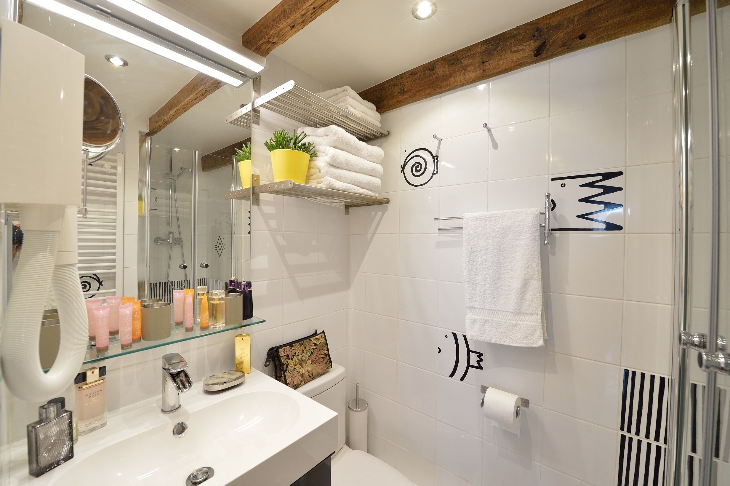 A modern bathroom with a glass shower enclosure, a white sink, and a towel rack.