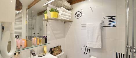 A modern bathroom with a glass shower enclosure, a white sink, and a towel rack.