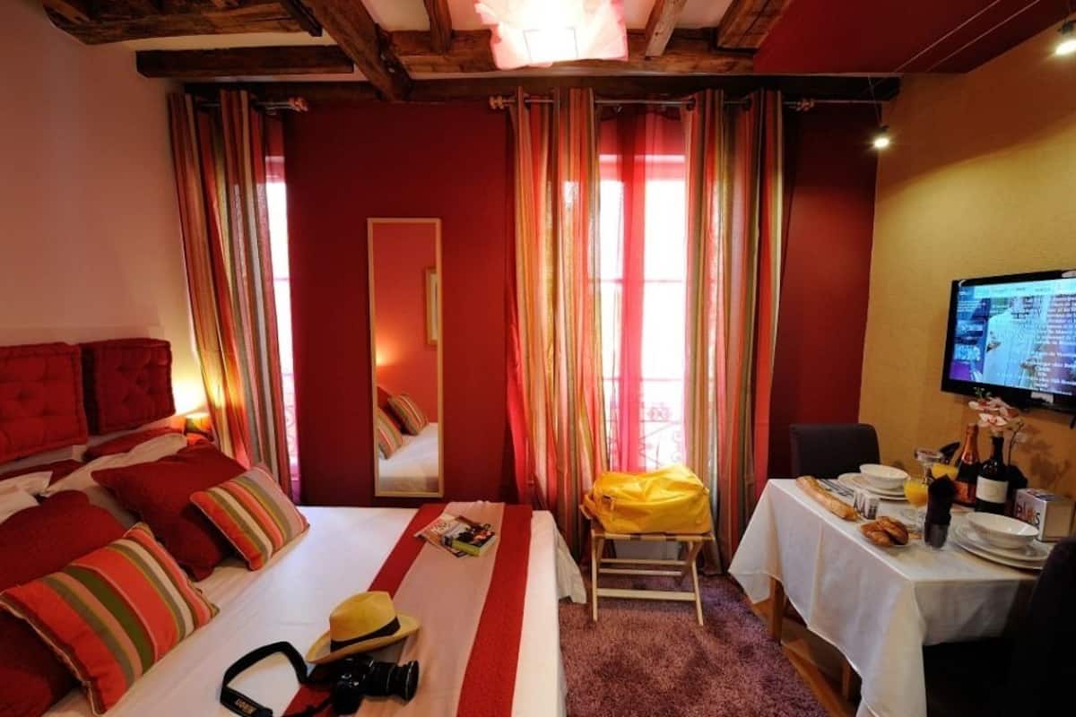 A hotel room with a bed, a dining table with breakfast items, a TV, and a mirror.
