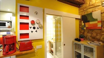 Une cuisine équipée d’un four à micro-ondes, d’un grille-pain rouge et d’un meuble contenant de la vaisselle en verre.