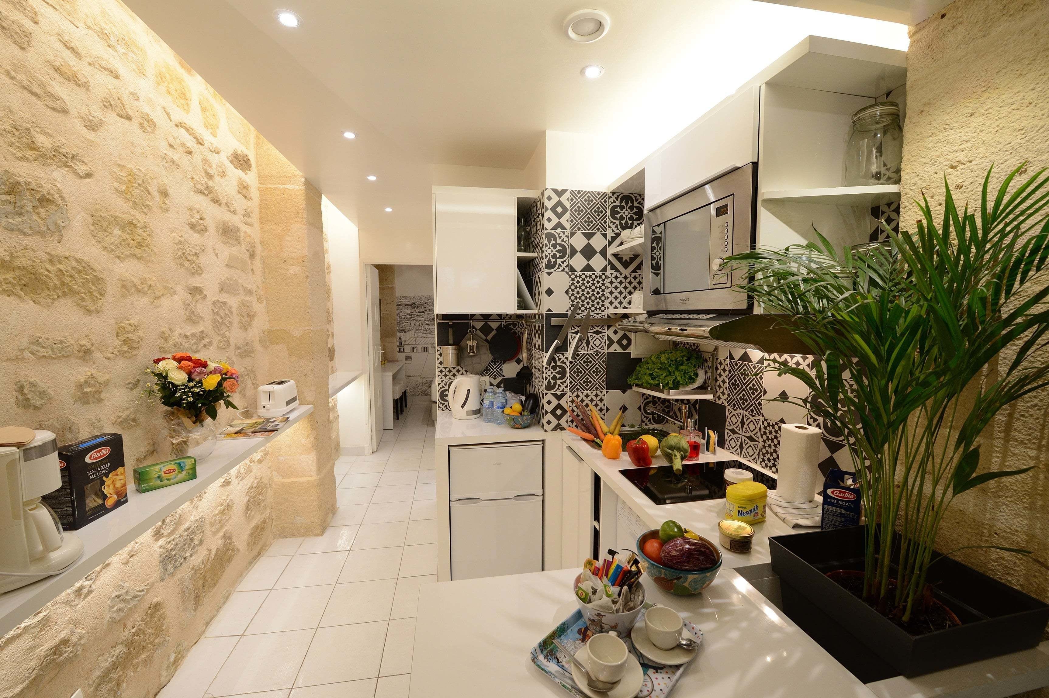 A compact kitchen with a stone wall, a refrigerator, a microwave, and a sink.