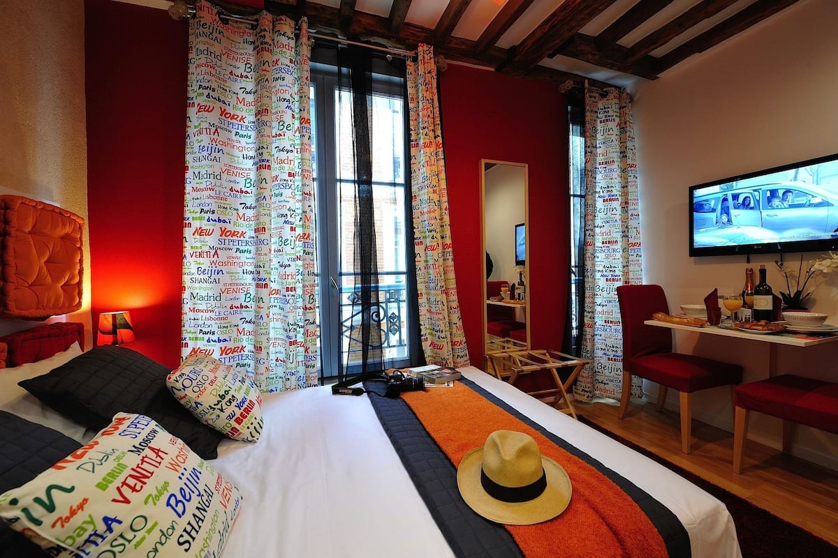 A hotel room with a bed, a TV, a desk, and a dining area.