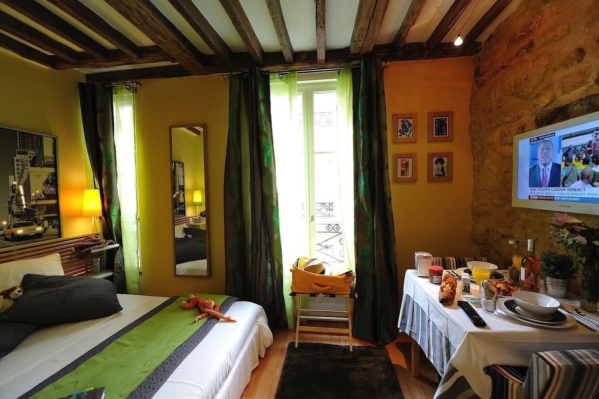 A hotel room with a bed, a table with breakfast items, a television, and a mirror.