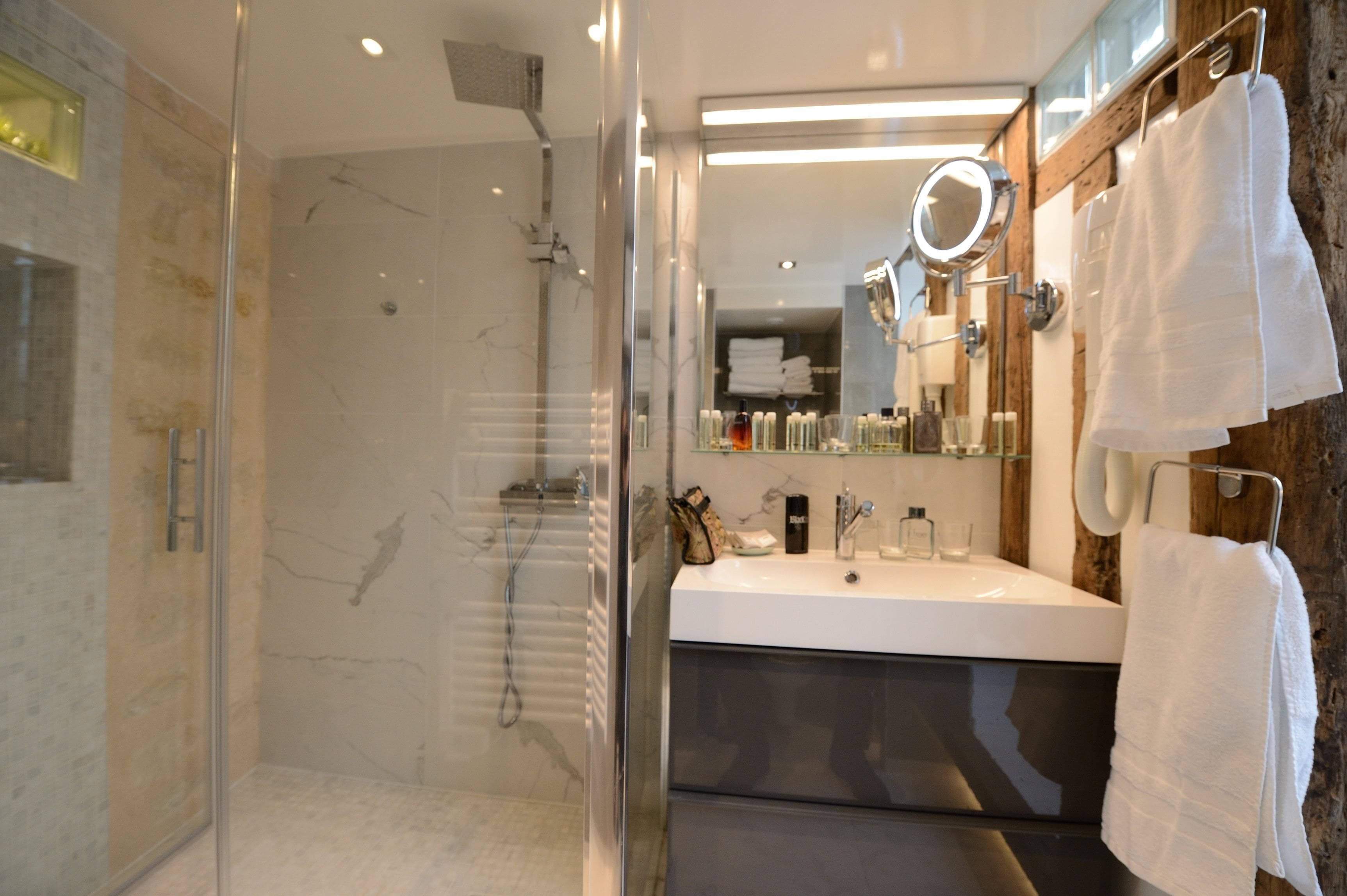 Ein modernes Badezimmer mit einer Duschkabine aus Glas, einem weißen Waschbecken mit Spiegel und Holzelementen.