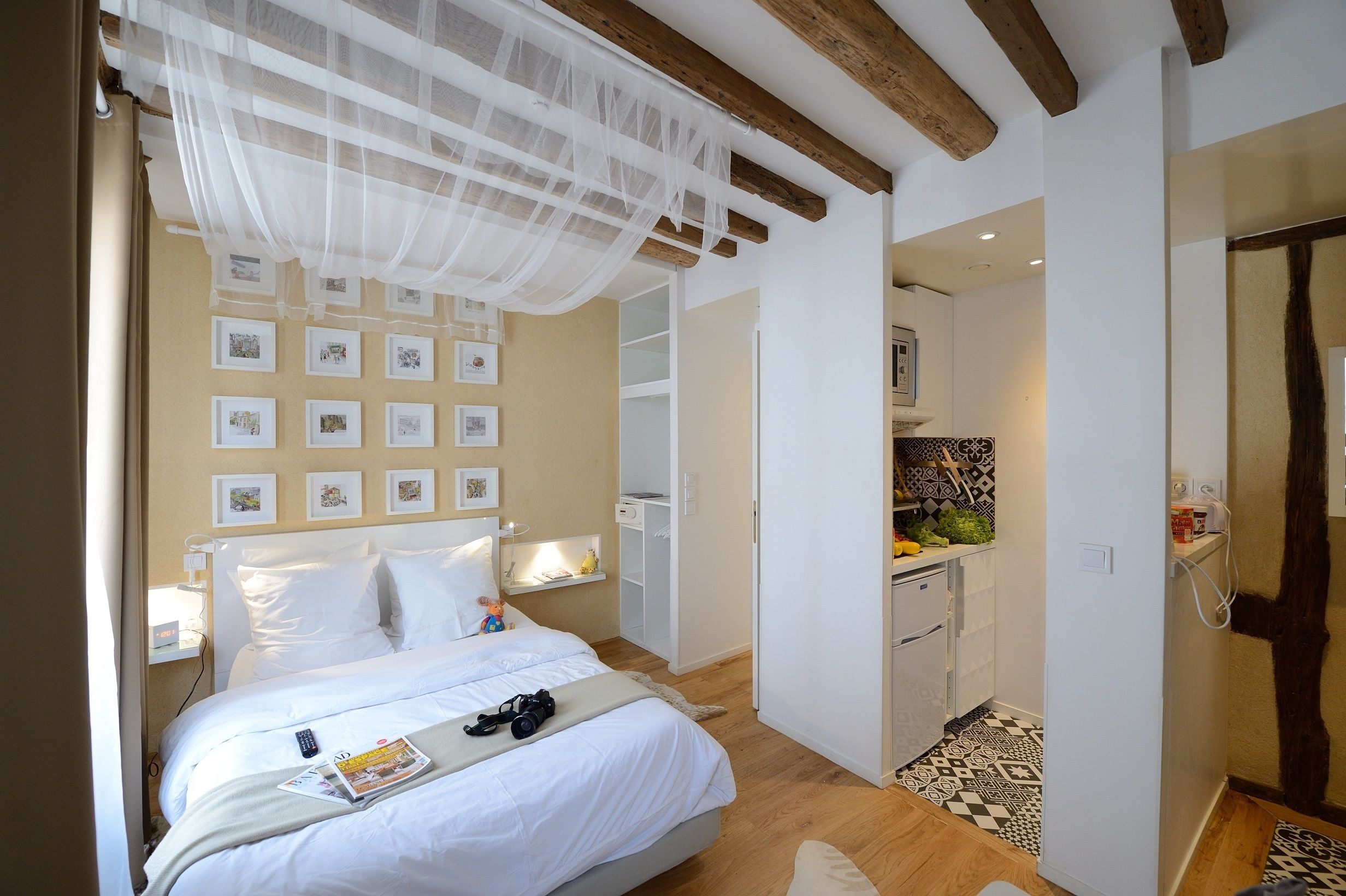 A bedroom with a bed, bedside table, and a small kitchenette.