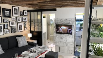 A dining area with a table set for four, a black sofa, and framed pictures on the wall.