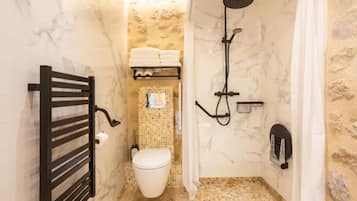 A compact bathroom with a shower, toilet, and towel rack.