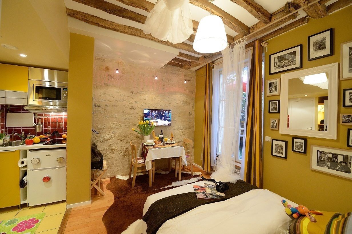 Una camera d'albergo compatta con angolo cottura, un letto, un'area pranzo e una TV.