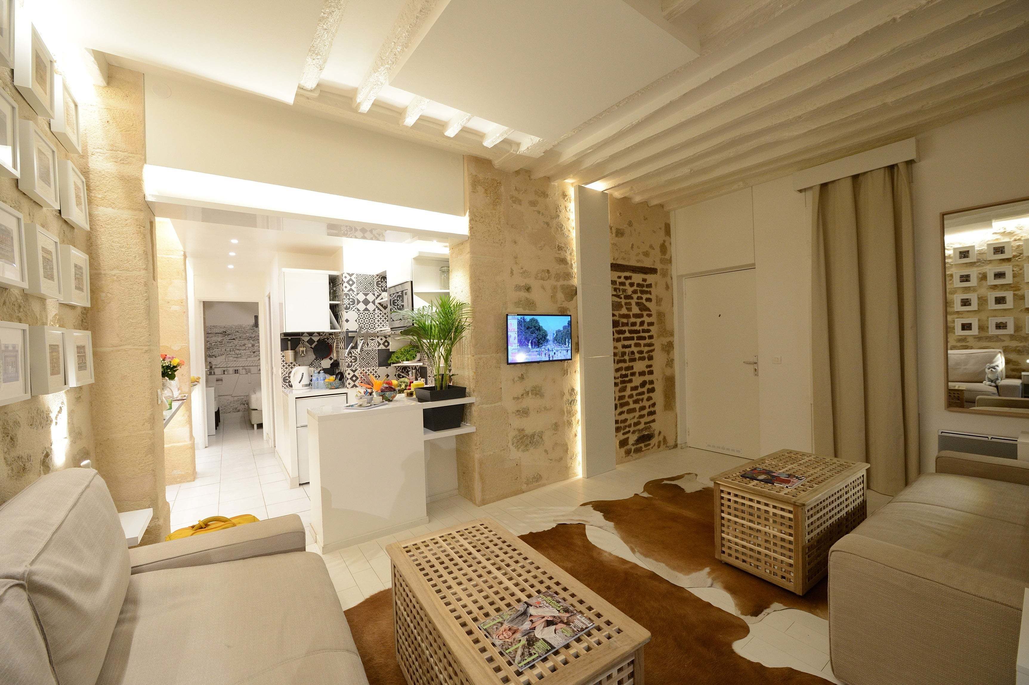 A modern living room with a sofa, a coffee table, and a television mounted on a stone wall.