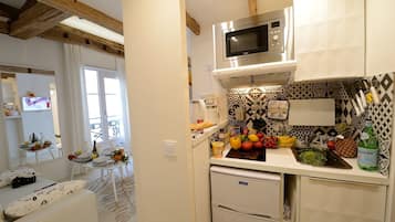 A kitchen with a microwave, a refrigerator, and a sink. There are fruits and vegetables on the counter.