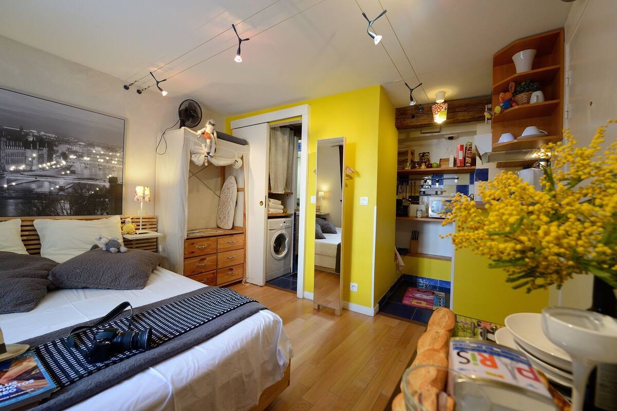 A bedroom with a bed, a nightstand, a lamp, and a window with a cityscape view.
