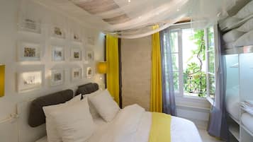 A hotel room with a bed, a window with curtains, and wall-mounted picture frames.