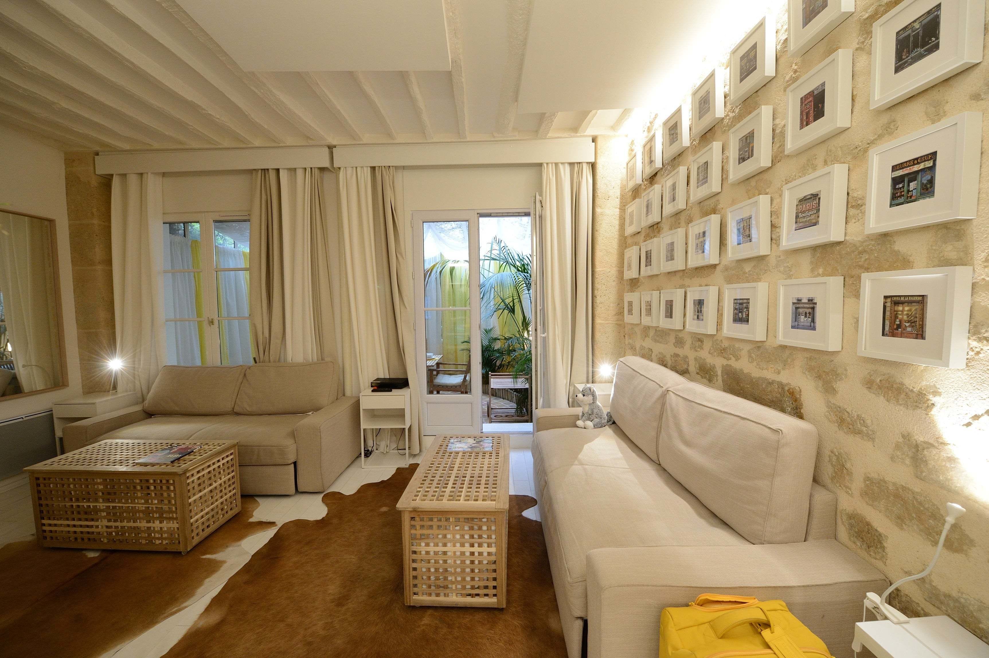 A cozy living room with a sofa, two wooden crates, a cowhide rug, and a wall adorned with framed pictures.