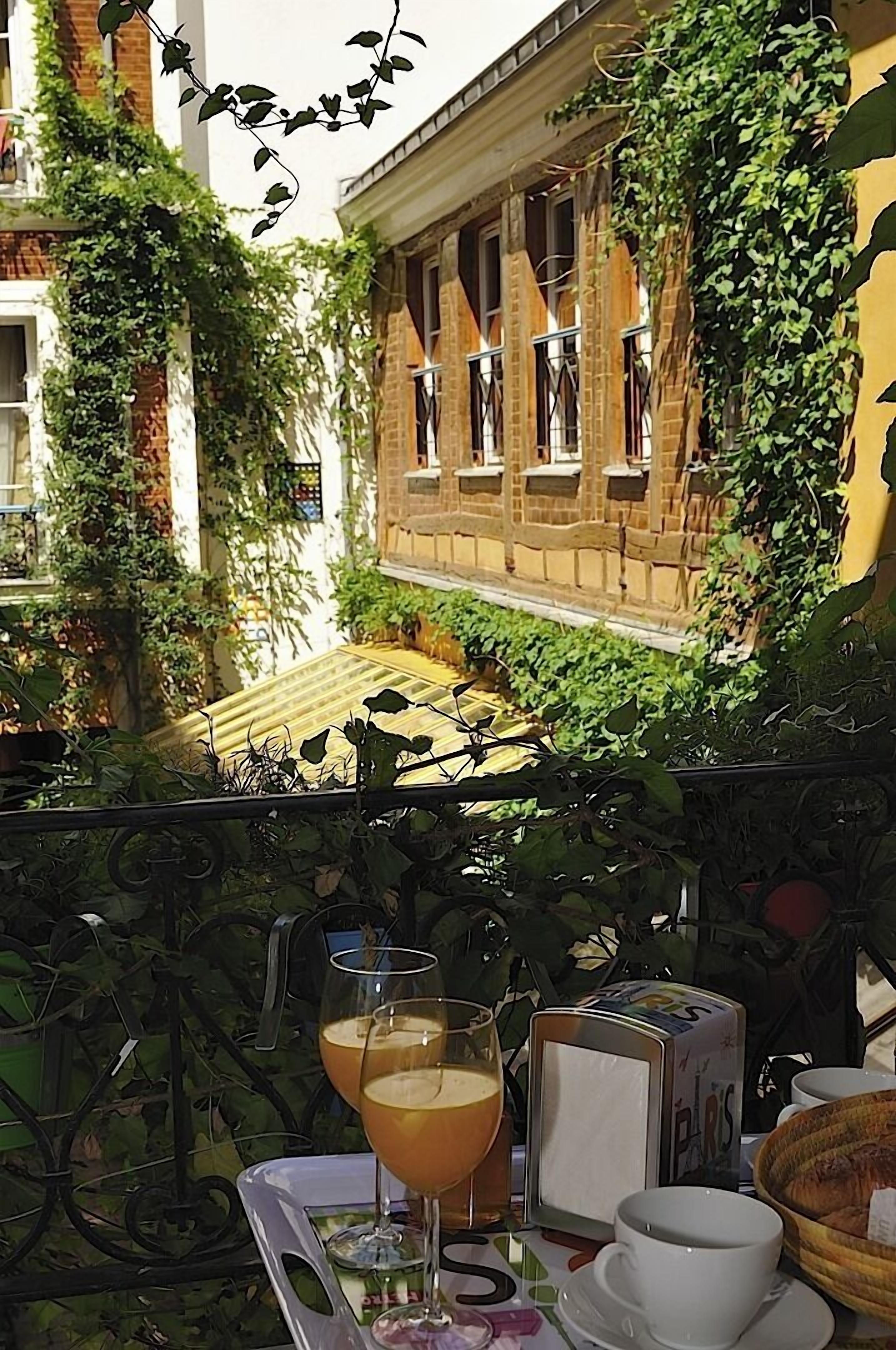 Une terrasse avec une table dressée pour deux personnes, des verres remplis d’une boisson, une boîte et un panier.