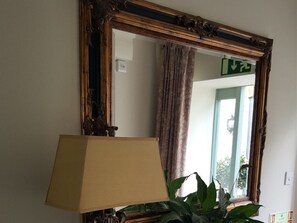 A mirror with an ornate frame, a lamp in front of it, and a plant beside the mirror. - The Natterjack Inn (Shepton Mallet)