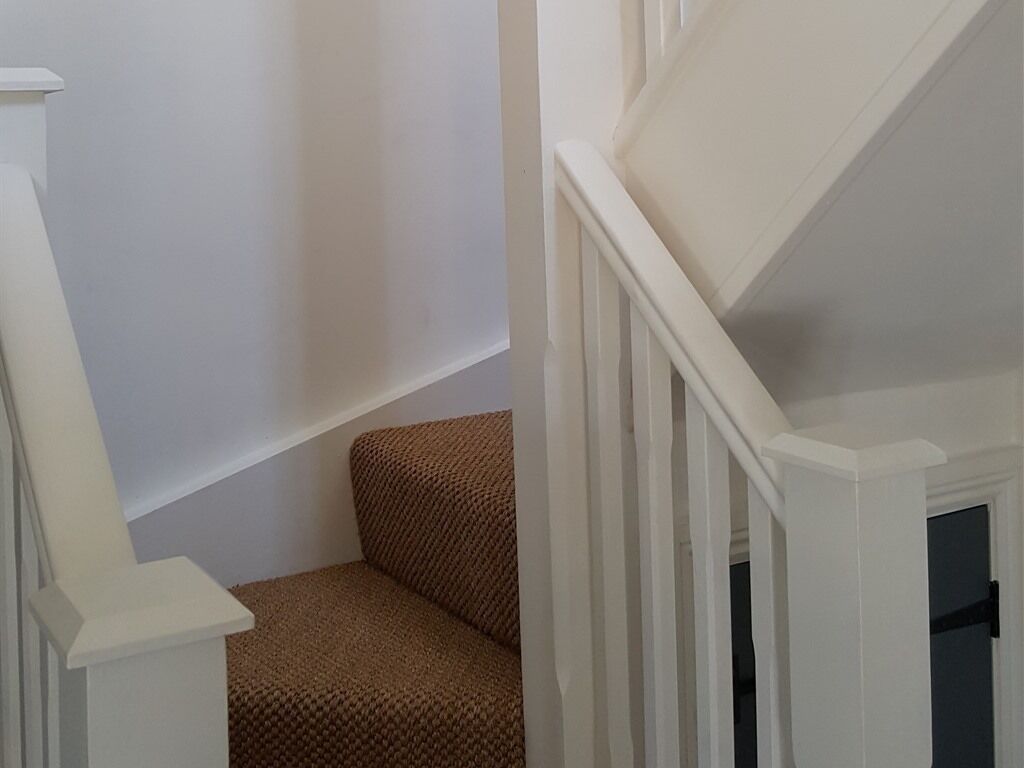 A staircase with white railings and a brown carpeted area.