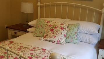 Classic bedroom with a floral-patterned bedspread and a wooden nightstand.