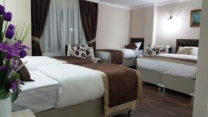 A hotel room with two beds, a large window with curtains, a vase of purple flowers, and a painting on the wall. - Beyazithan (Istanbul)