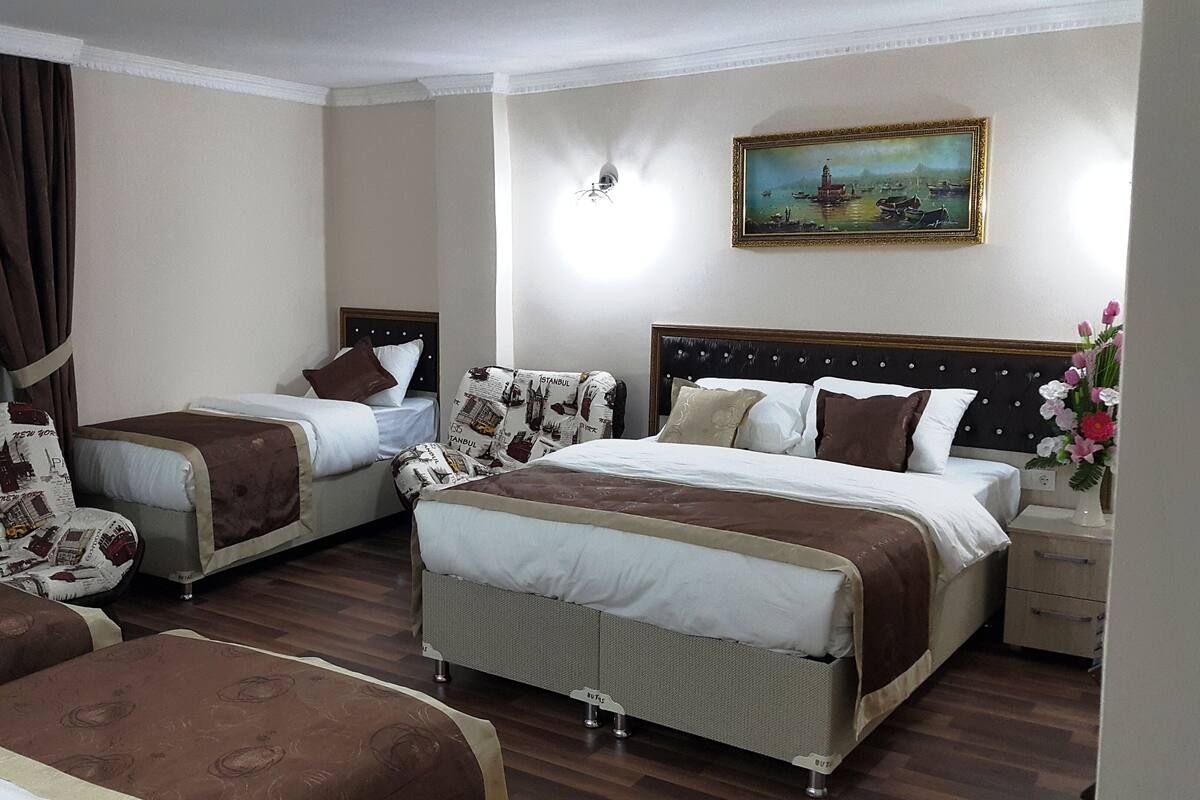 Une chambre d’hôtel avec deux lits, un tableau au mur et une fenêtre avec des rideaux.