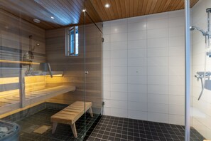 A sauna with a glass enclosure, wooden benches, and a tiled floor.