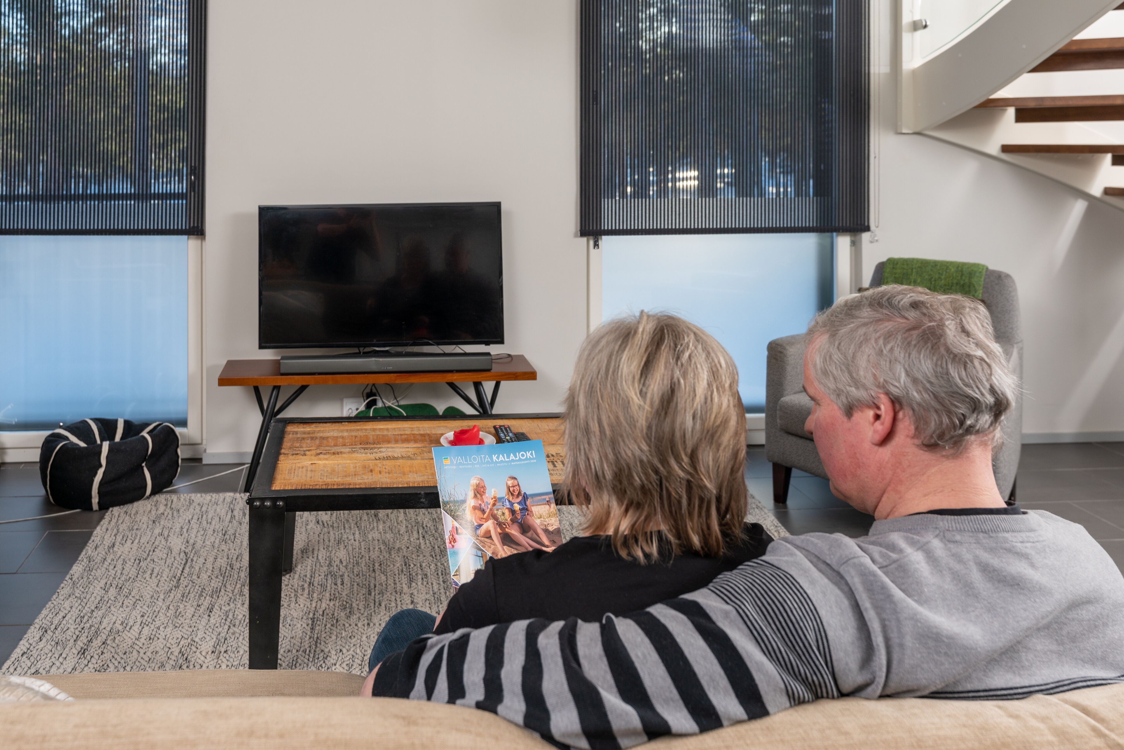 En stue med sofa, fjernsyn og sofabord med et magasin.