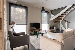 A modern living room with a sofa, a coffee table, a TV, and a staircase.