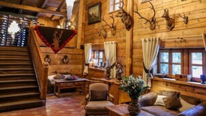 Un interior rústico de madera con chimenea, comedor y escalera.