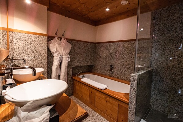 Un baño moderno con un lavamanos independiente, una bañera y una ducha con mampara de vidrio.