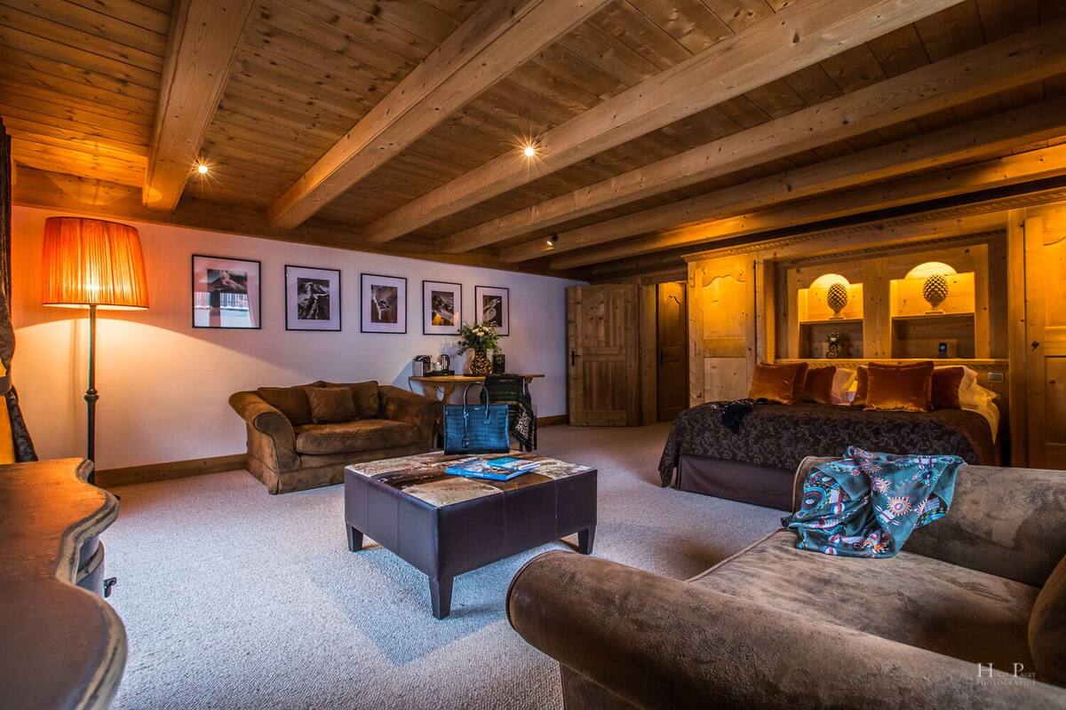 A cozy room with a wooden ceiling, a sofa, a coffee table, and a bed.