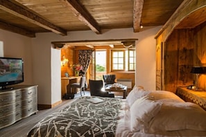 A bedroom with a bed, a desk, and a television.