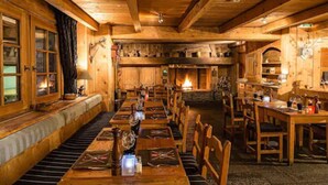 Un interior de madera acogedor con una larga mesa de comedor, bancos y una chimenea.