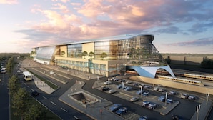 A modern building with a unique curved roof, surrounded by a parking area and a train station. - The Ankara Hotel (Ankara)