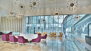 A spacious lobby with modern chandeliers, a large white table, and purple chairs. - The Ankara Hotel (Ankara)