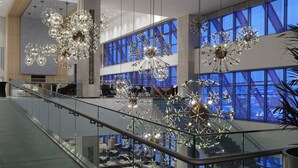 A modern interior with multiple levels, glass railings, and decorative chandeliers. - The Ankara Hotel (Ankara)