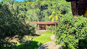 Un jardin luxuriant avec un sentier menant à un bâtiment doté d’un toit rouge.