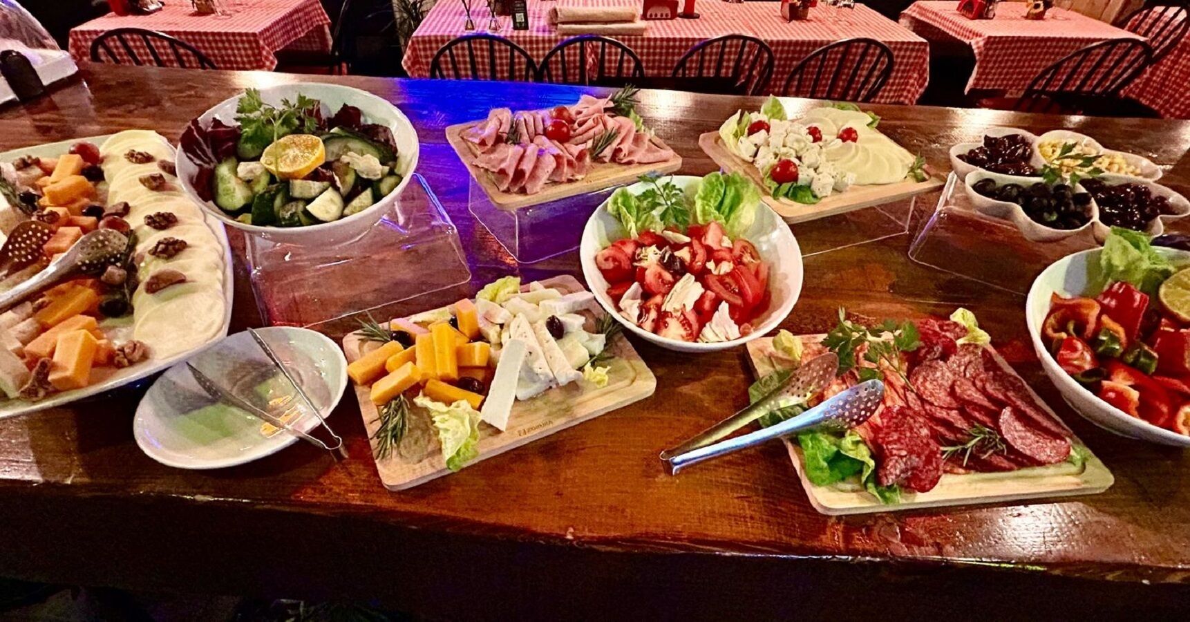 A buffet table with various food items including salads, cheeses, and meats.