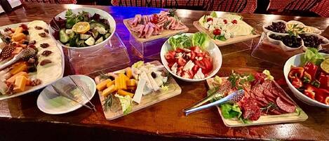 A buffet table with various food items including salads, cheeses, and meats.